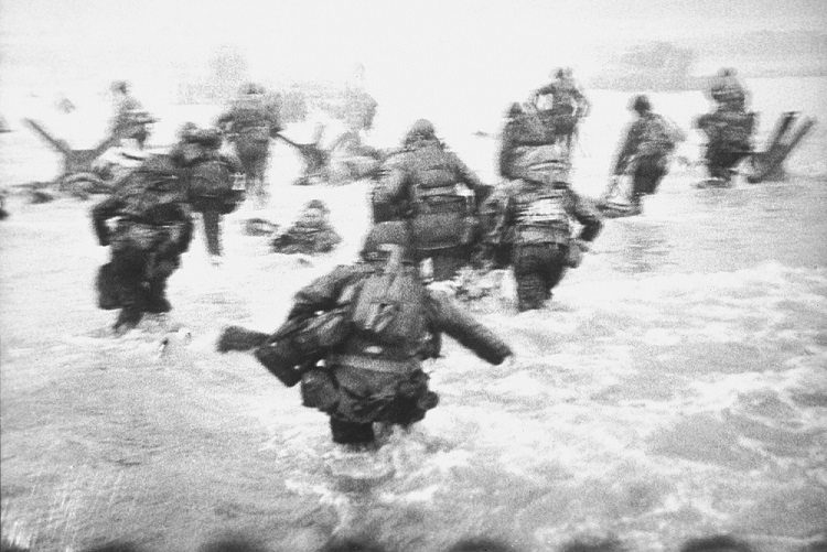 Black and white photo of troops storming the beach at Normandy by Robert Capa