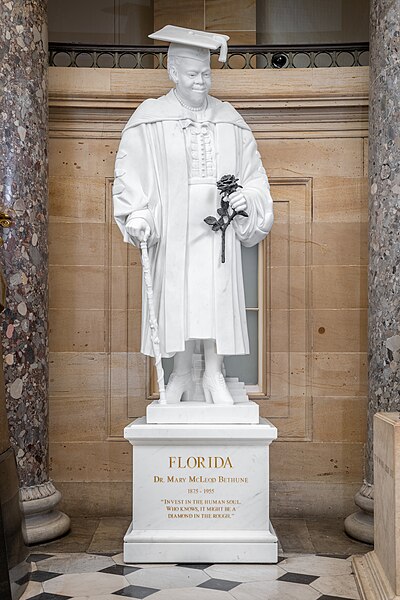 Photo of Mary McLeod Bethune statue in the U.S. Capitol, depicting Dr. Bethune in cap and gown and holding a black rose that contrasts with the white of the rest of the sculpture