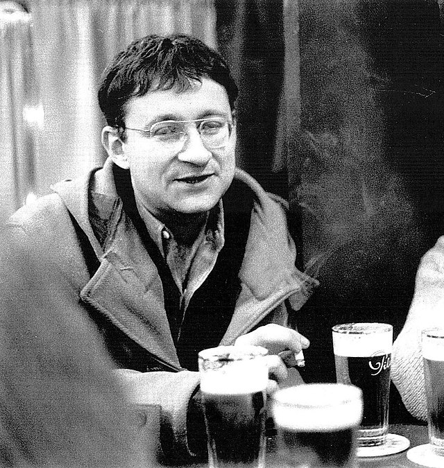 Black and white photo of Guy Debord smoking and drinking a pint of beer