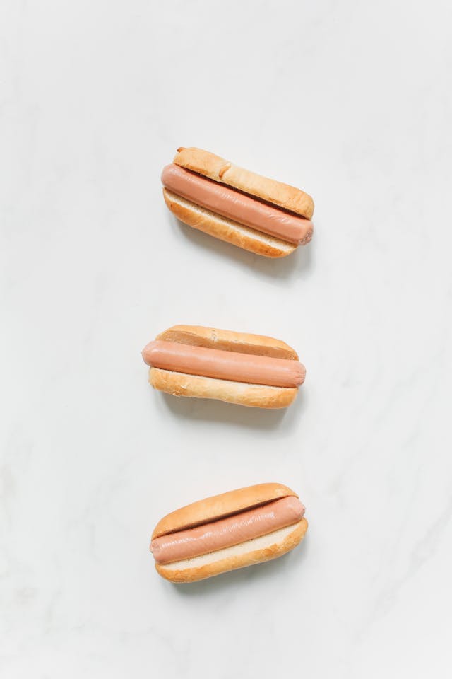 Three pale-looking hot dogs on buns, photographed from above