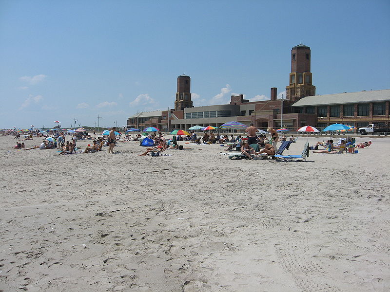 A photo of the beach at Jacob Riis Park, showing a crowd of people with chairs and umbrellas on the sand