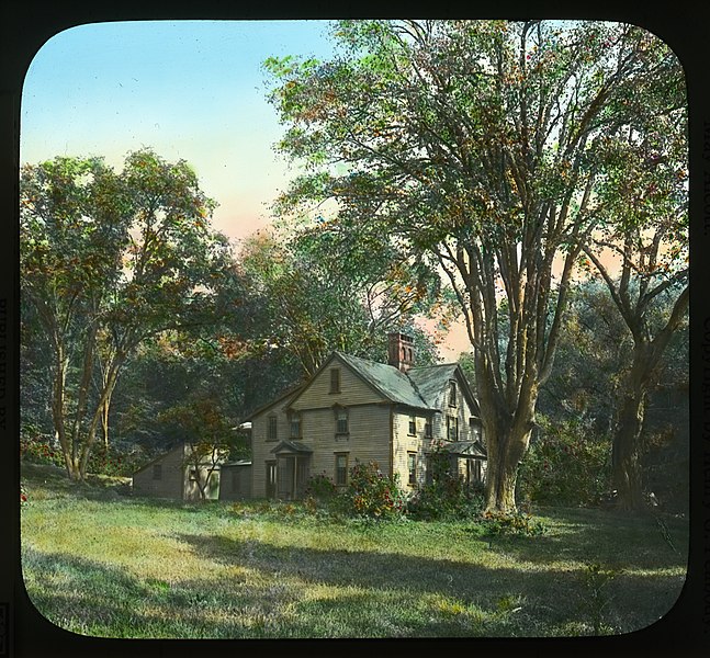 Older-looking color image of the home of Louisa May Alcott, a white farmhouse surrounded by trees